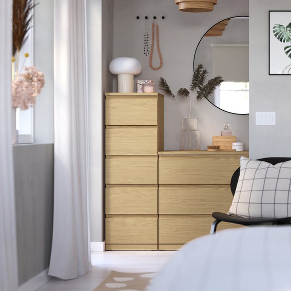 Modern bedroom with light wooden STORKLINTA dresser, four drawers, top decor, large mirror, pillow.
