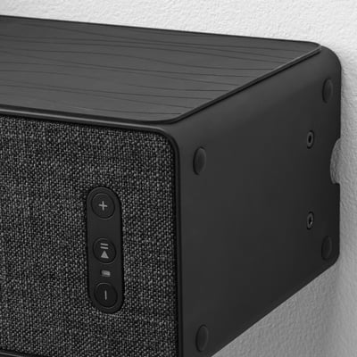 Black speaker mounted on wall bracket, controls visible.