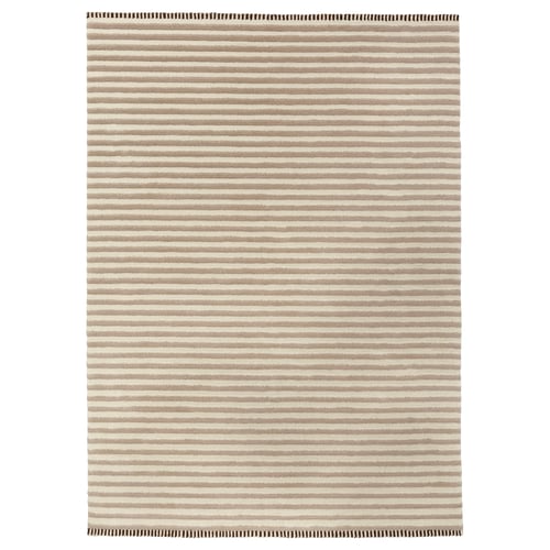 This image shows the TÅGSPÅR rug, a beige and white striped wool rug with a 3d effect.