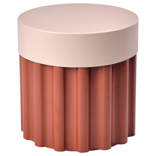 A tesamman side table. Its round with corrugated edges in pink and red-brown colours. Made of steel and plastic, it has a lift-off lid for storage.