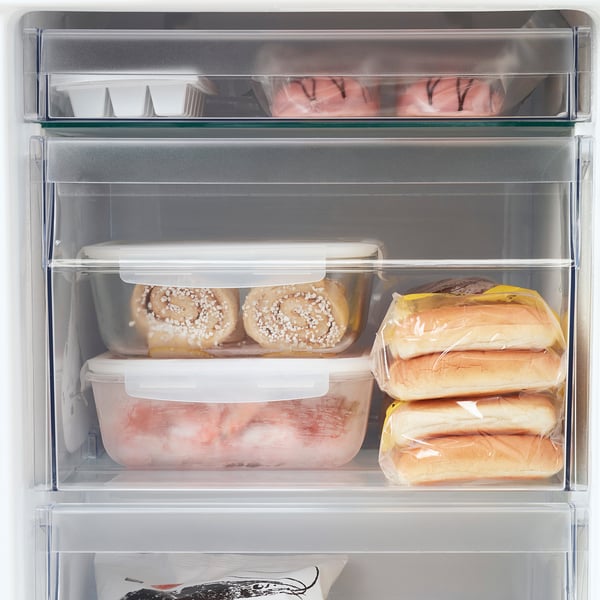 Clear fridge compartment with adjustable shelves, holding covered pastries and wrapped bread.