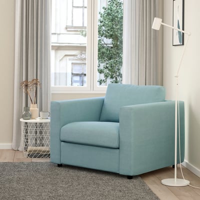 Modern room with light blue VIMLE armchair, large window, floor lamp, and side table with vase.