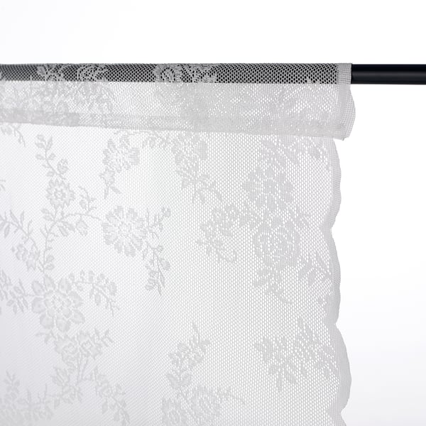 A sheer white curtain with leaf patterns is displayed, showcasing how to hang it via a back pocket for a tailored look.