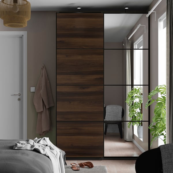 Bedroom with AULI sliding closet doors, one mirrored, the other wooden. Reflective surface doubles room space, with a soft-close mechanism.