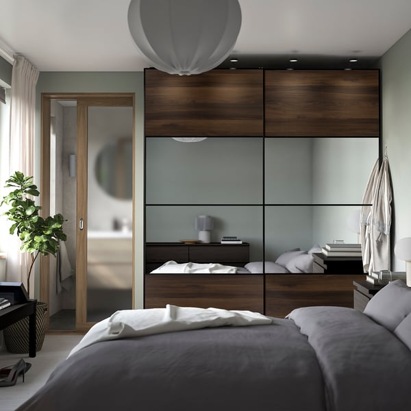 Modern bedroom with AULI dark brown glass sliding door, mirrored effect, slim frames, matching furniture, plant, soft lighting.