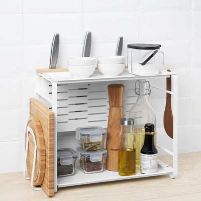 White 2-tier kitchen organiser with wooden accents, holding bowls, knives, spices, oil bottles, and cutting boards.