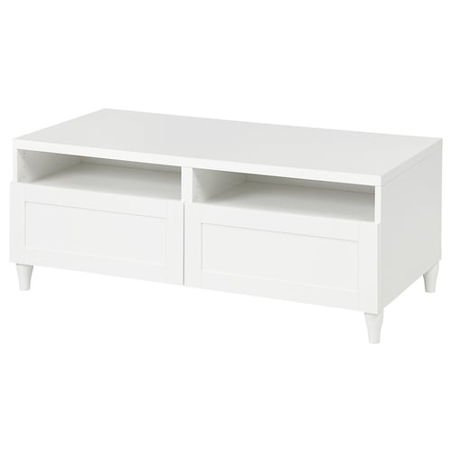 A white BESTÅ coffee table with drawers and open shelves. The table has a sleek, modern design with tapered legs.