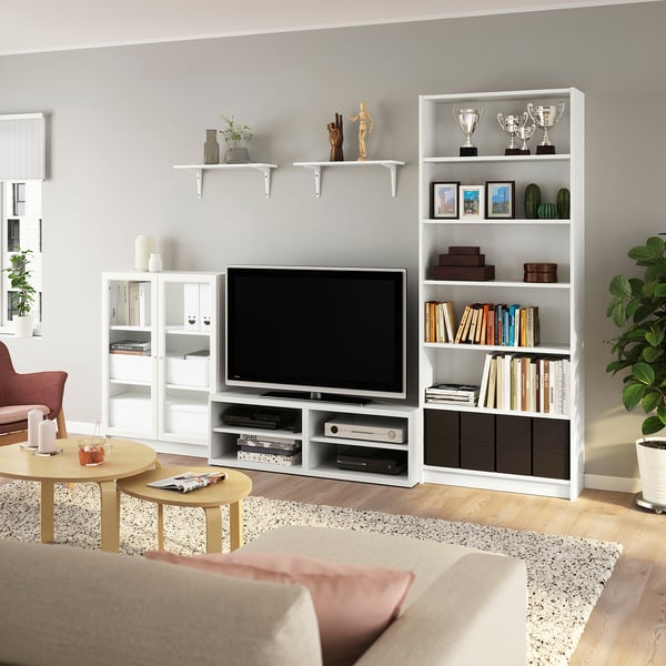 Cosy living room with BILLY tv bench, plant, shelves, trophies, books, beige couch, coffee table with drinks.