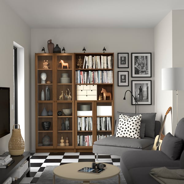 Modern living room with wooden BILLY bookcase, grey couch, patterned pillows, checkerboard floor, guitar, and coffee table.