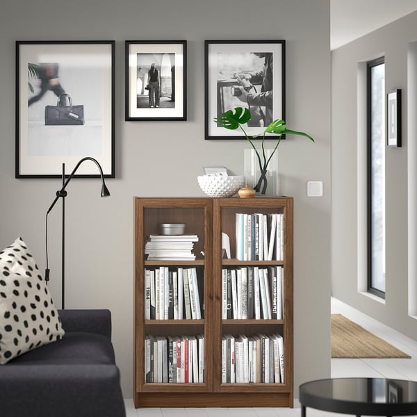 Modern living room with BILLY bookcase, black sofa, and polka dot pillow, three framed pics above.