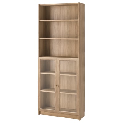 A BILLY light brown bookcase with glass doors. It has five shelves, three open and two behind glass.