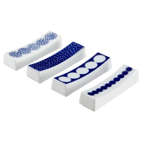 Four white porcelain chopstick holders with blue patterns. From left, swirls, dots, circles, and dots. Curved, white with blue accents.