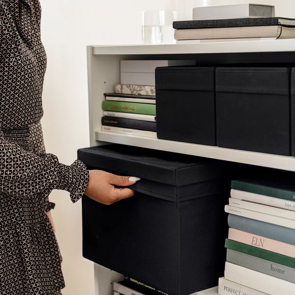 Pulling DRÖNA storage box from bookcase.