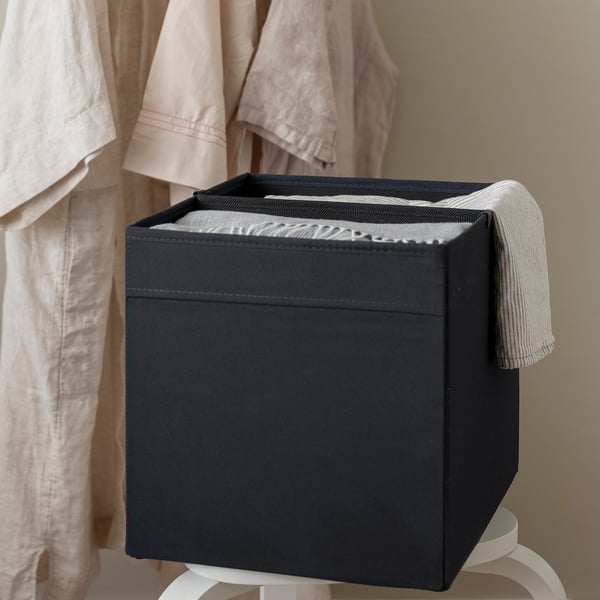 Black storage box with divider on white stand, organising towels.
