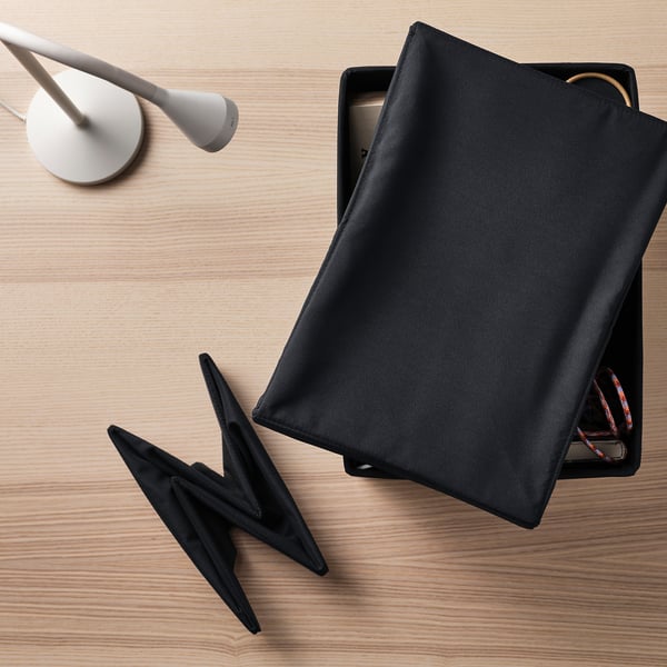 Black fabric lid on wooden surface, partially covering box with visible cables, demonstrating its use to protect contents from dirt and dust.