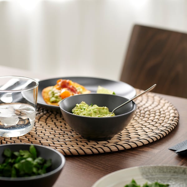 Table with bowls, food, and glass. Stoneware bowls hold guacamole and other dishes.