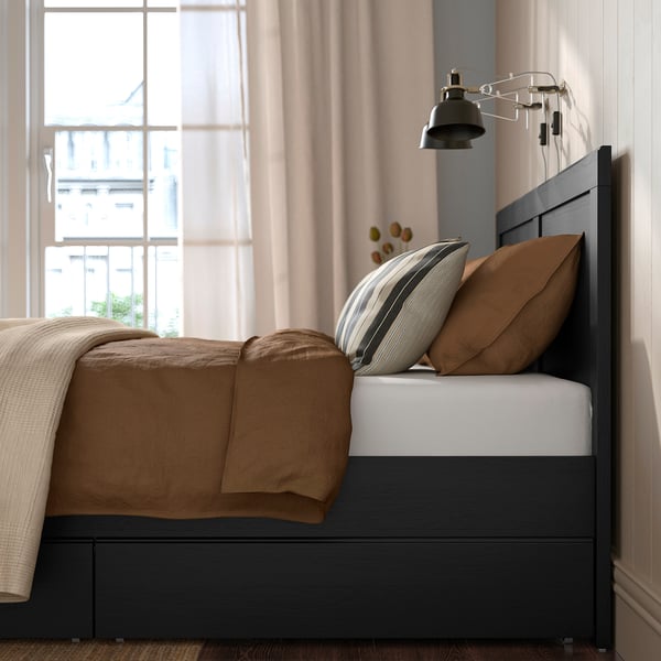 Bedroom scene with FÅGELFJÄLLET bed; storage boxes beneath, pillows, comforter, and wall light.