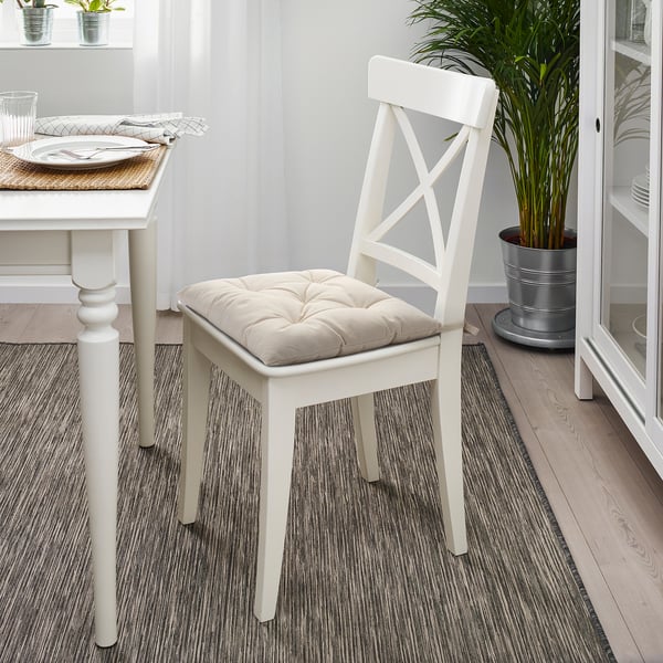 White GURLI chair pad on matching chair at dining table with plants and plates.