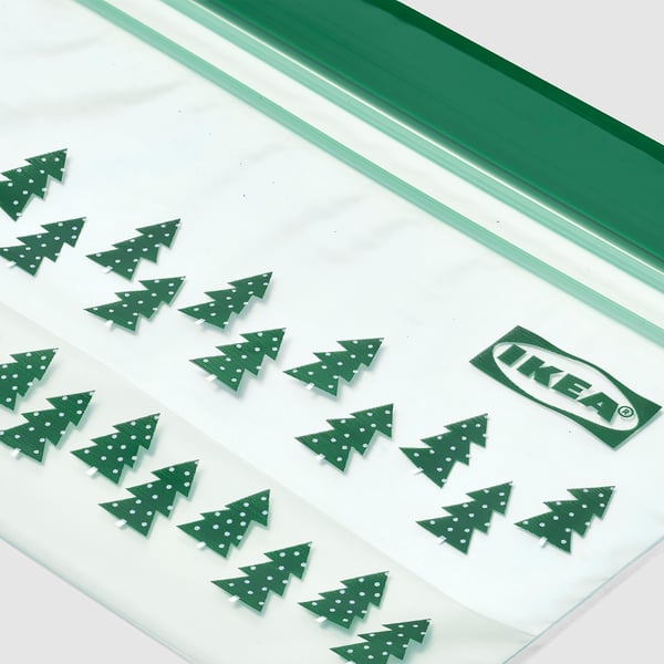 Small green christmas tree-shaped decorations lined up on a white transparent plastic food bag. The IKEA logo is visible on the bag.