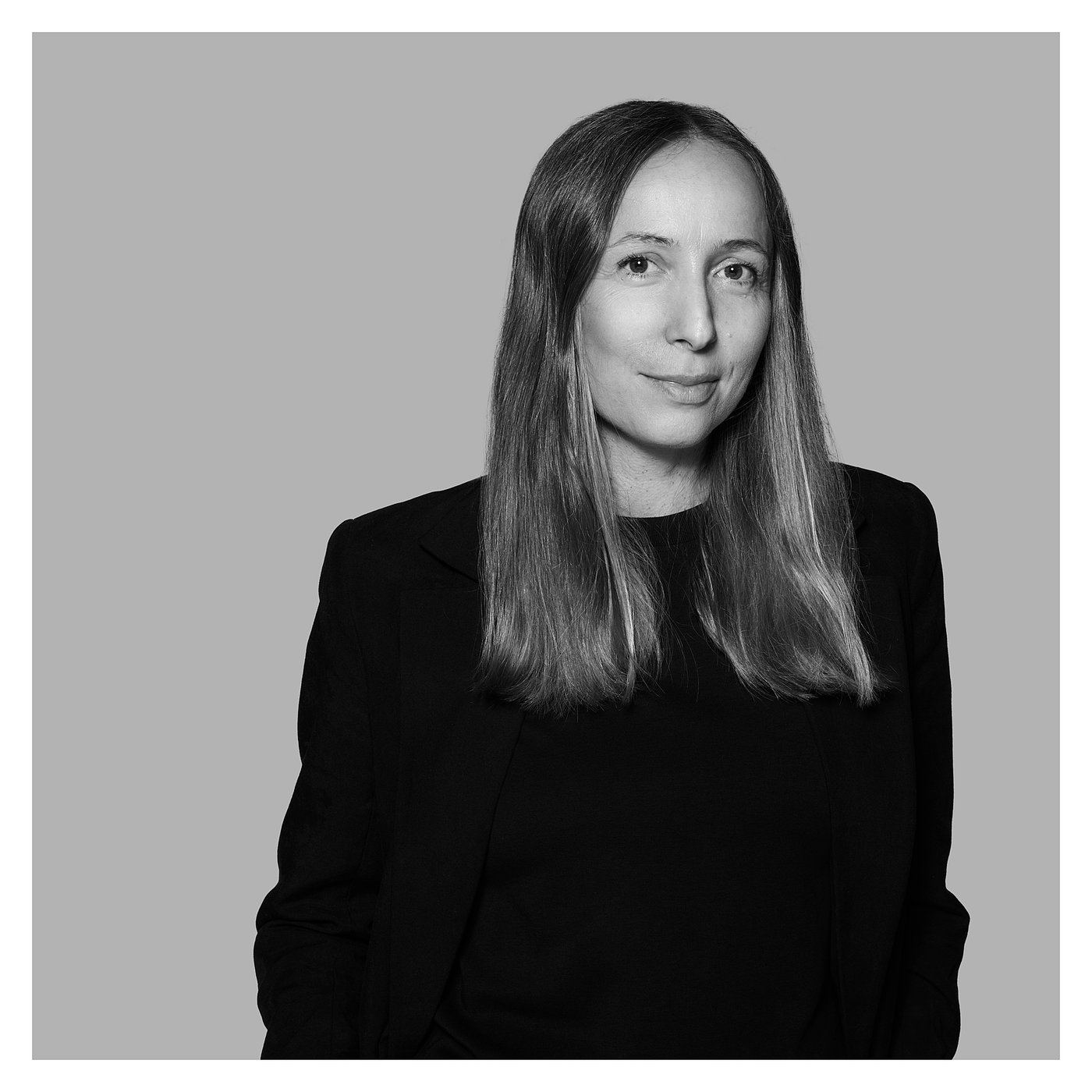 Black and white portrait of Maja Ganszyniec with long hair, dressed in a black outfit, posing against a plain background.