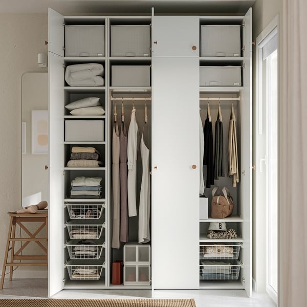 Organised white wardrobe with medals, clothes, and bins on shelves.