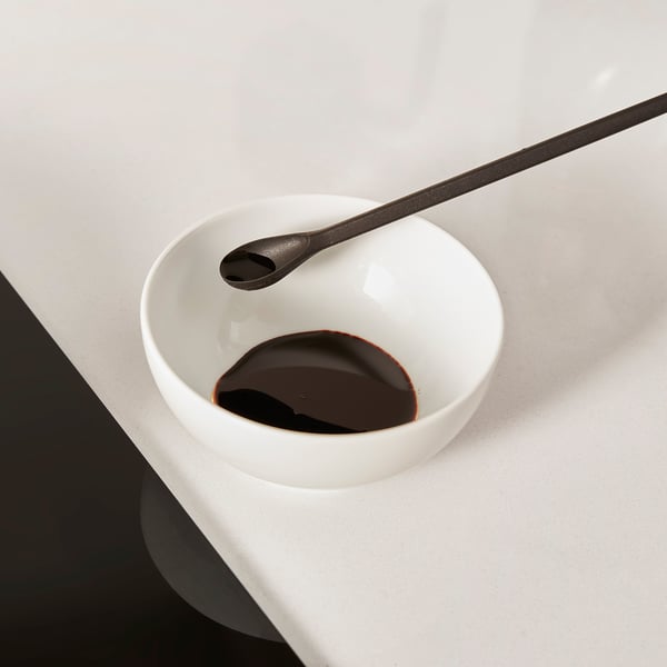 Small bowl with spoon; likely used for tasting or mixing, shown with a sticky substance.