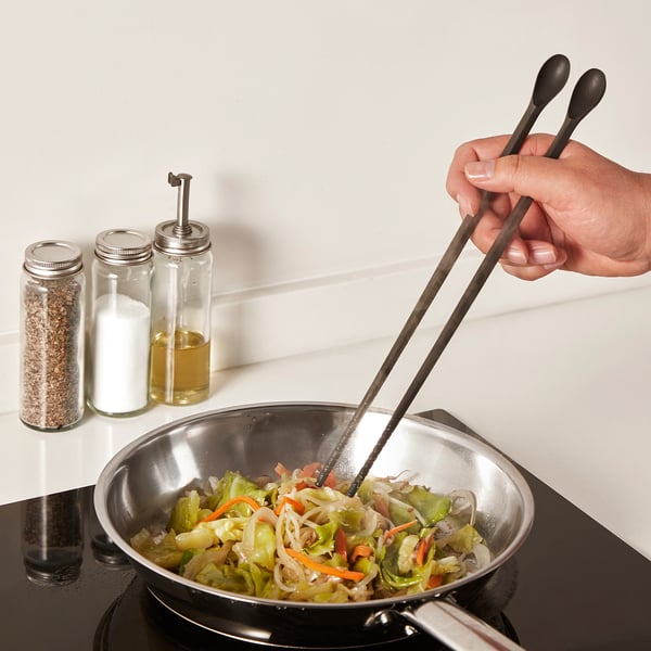 Hand stir-fries veggies in pan using LUNGROT, showing its cooking and tasting utility.