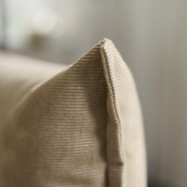 Close-up of a beige sofas cushion edge showing high-quality stitching and texture.
