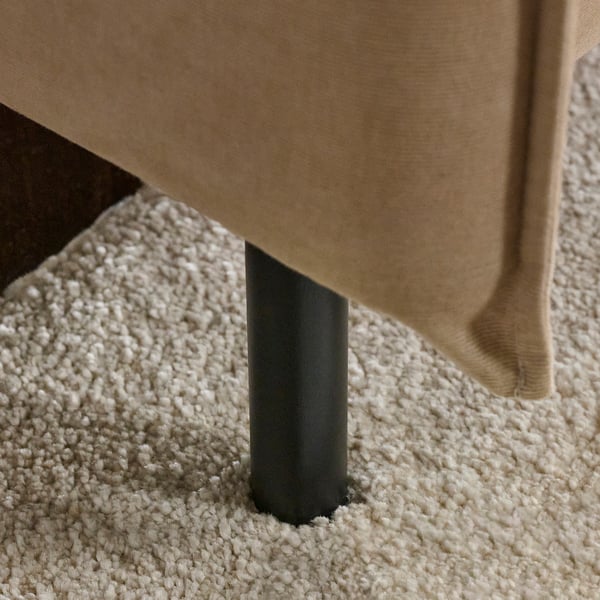 Modern sofa with sleek black legs, beige upholstery on plush carpet. High-quality design.