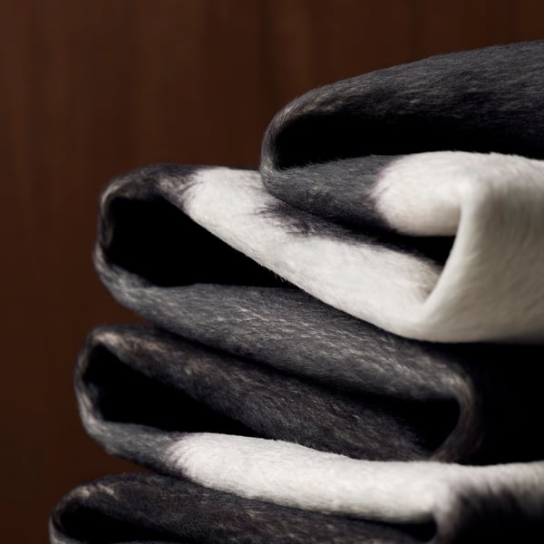 Stack of folded black and white rugs; soft, textured, high-quality appearance.