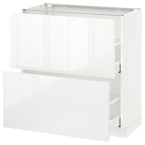 A white, glossy kitchen cabinet. Its a METOD kitchen base unit with a drawer and two shelves, all in pristine white.