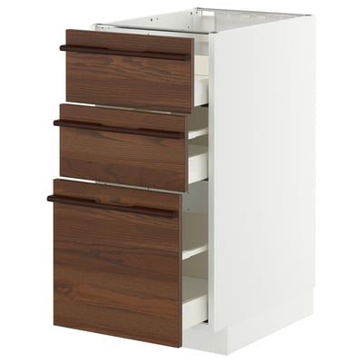 A white METOD kitchen cabinet with dark brown stained ash veneer drawers featuring wooden handles.