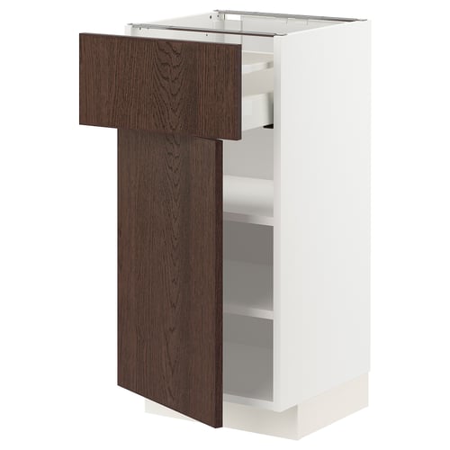A white METOD kitchen cabinet with a dark brown wooden door. The door is partially open, revealing adjustable shelves inside.