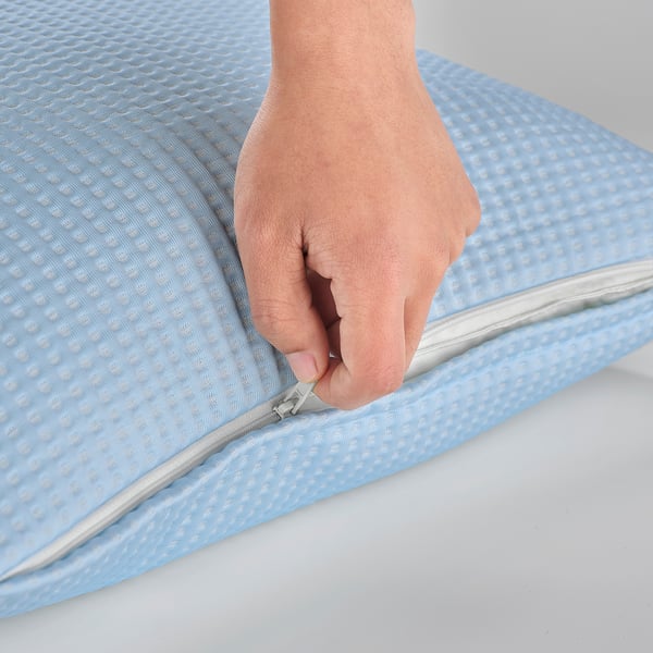 Person zipping up a cool, textured blue cushion cover.