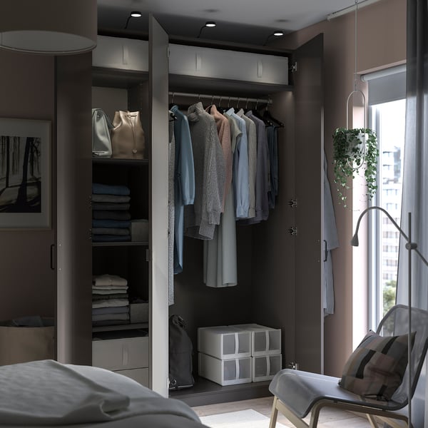Organised closet with PAX storage unit displaying clothes, bags, and folded items. Modern design featuring grey components and recessed lighting.