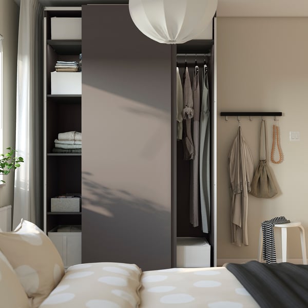 Modern bedroom with open wardrobe, lamp, and patterned bed.