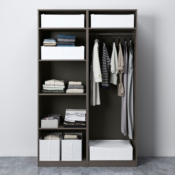 A PAX wardrobe with sliding doors holds clothes on hangers and folded on shelves, with storage boxes.