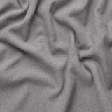 Close-up of soft, folded grey fabric. Textured, recycled polyester material shown in delicate waves.