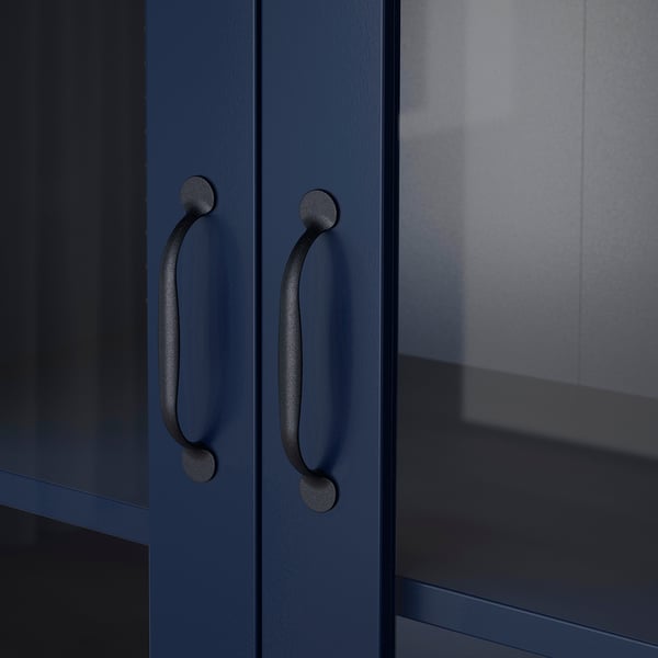 Dark cabinet with rounded black handles. Glass door reflects light, showing quality craftsmanship.
