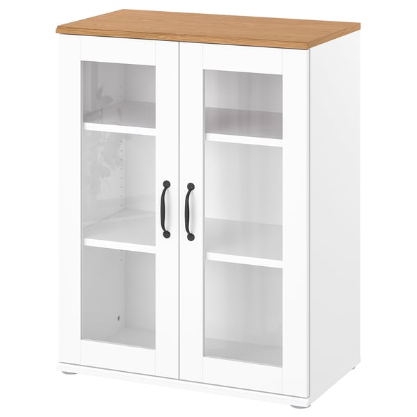 A white SKRUVBY storage cabinet. The top is light wood. It has glass doors with metal handles, displaying empty shelves inside.