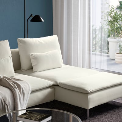 Modern white sectional sofa with fashionable, deep seats, near window and plants.