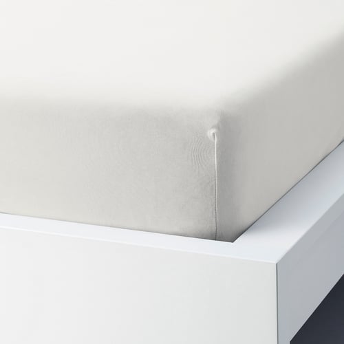 A fitted white cotton sheet with slight texture, elastic corners, covering a mattress on a bed frame.