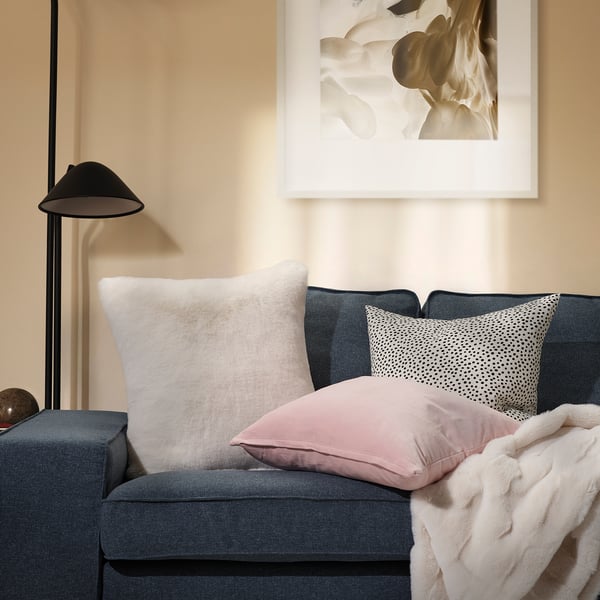 Cosy room with blue sofa, TORPSPIREA & pillows, white blanket, tall lamp, framed art.