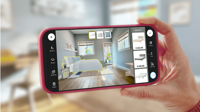 A hand holding a mobile device showing a scanned room with added IKEA dorm decor and furniture in IKEA Kreativ. The actual room is partially visible in the background.