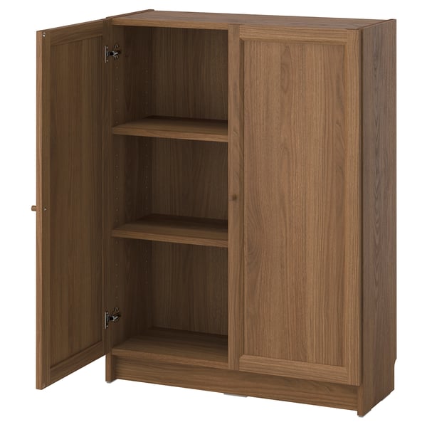 A BILLY bookcase in walnut colour, featuring two closed doors and adjustable shelves. Its made of wood with a simple, rectangular design.