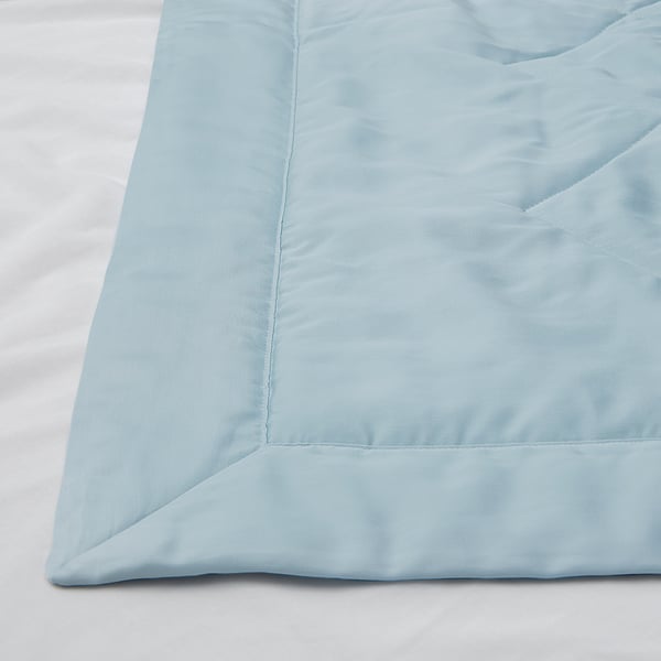 Light blue bedding with smooth texture and subtle pattern, laid neatly on bed.