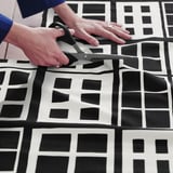 Person cuts black and white patterned fabric with scissors, likely for sewing or crafting.