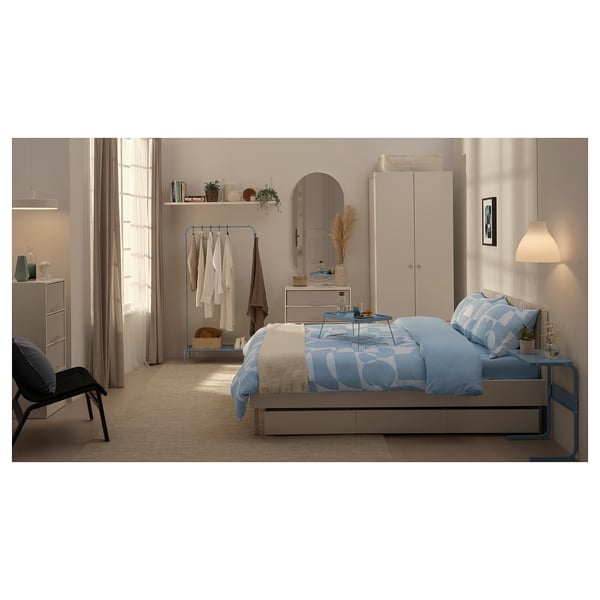 Bedroom with blue bedding, white wardrobe, and wooden chair.