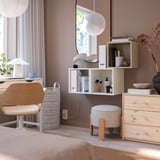 Modern bedroom with wall-mounted EKET storage, books, pink walls & wooden dresser.