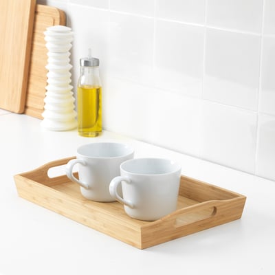 Wooden tray holding two white mugs on kitchen counter.